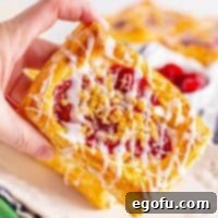 Buttery Cherry Crumble Danishes 16 Square image close up of hand holding one Cherry Crumble Danish.