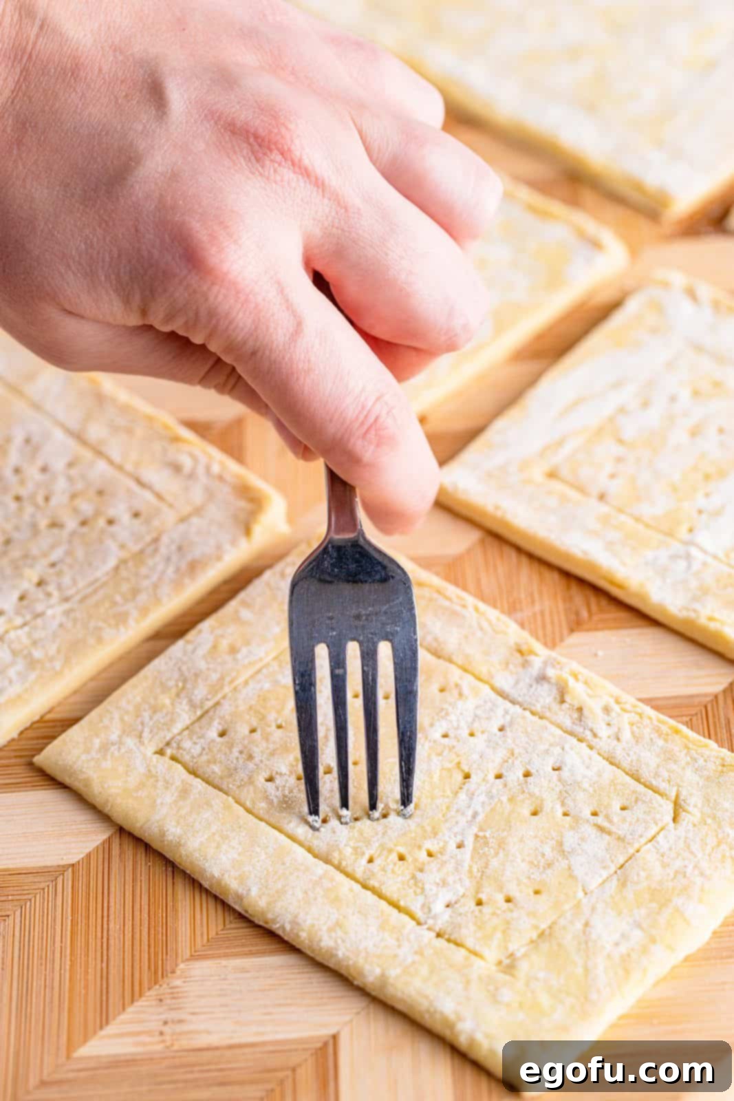 Buttery Cherry Crumble Danishes 8 Fork poking holes in puff pastry.
