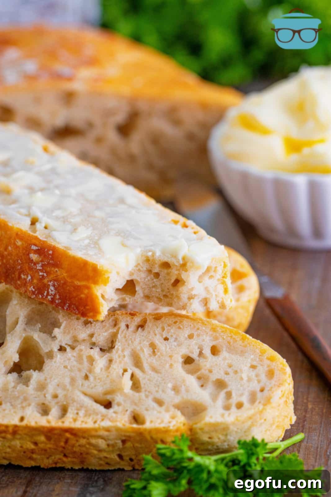 A slice of buttered No-Knead Dutch Oven Bread with a bite taken out, highlighting its soft interior.