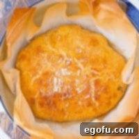 A perfectly golden, round loaf of No-Knead Dutch Oven Bread baked in a Dutch oven.