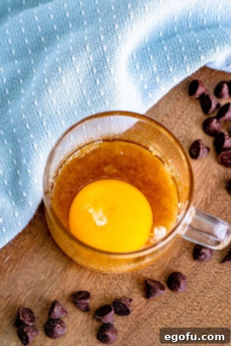 egg yolk added to melted brown sugar in a clear mug.