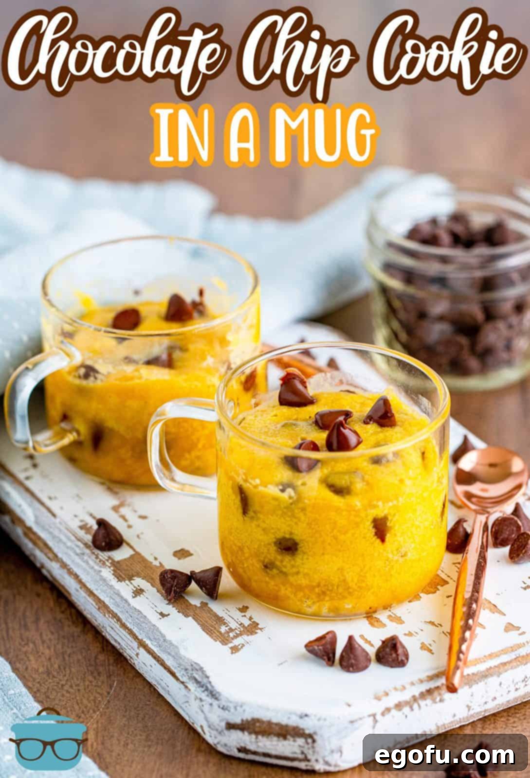 Chocolate Chip Cookies in two clear mugs shown on a white serving board with chocolate chips scattered around. 
