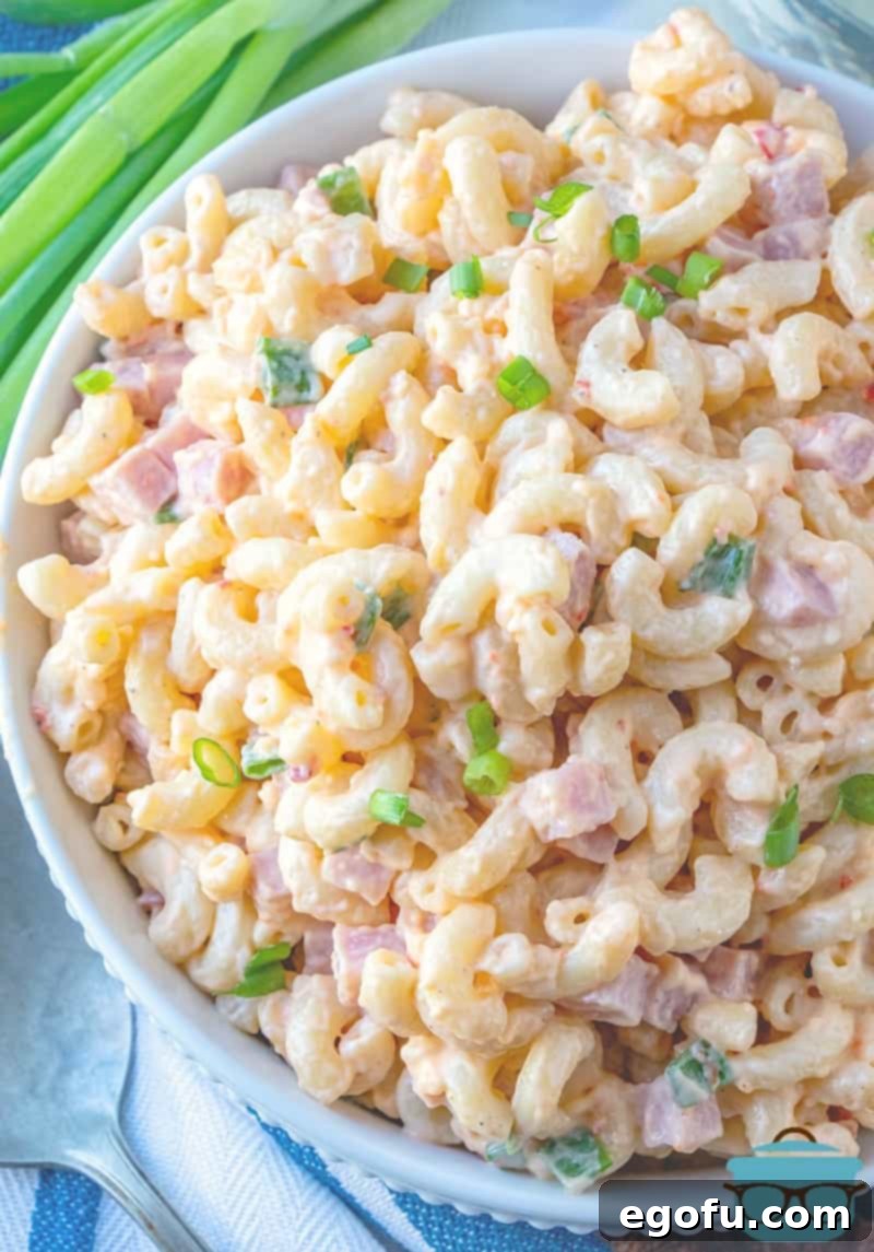 Homestyle Pimiento Macaroni Salad 2 Pimiento Cheese Macaroni Salad with Ham shown served in a large white bowl with a sprig of green onions in the background.