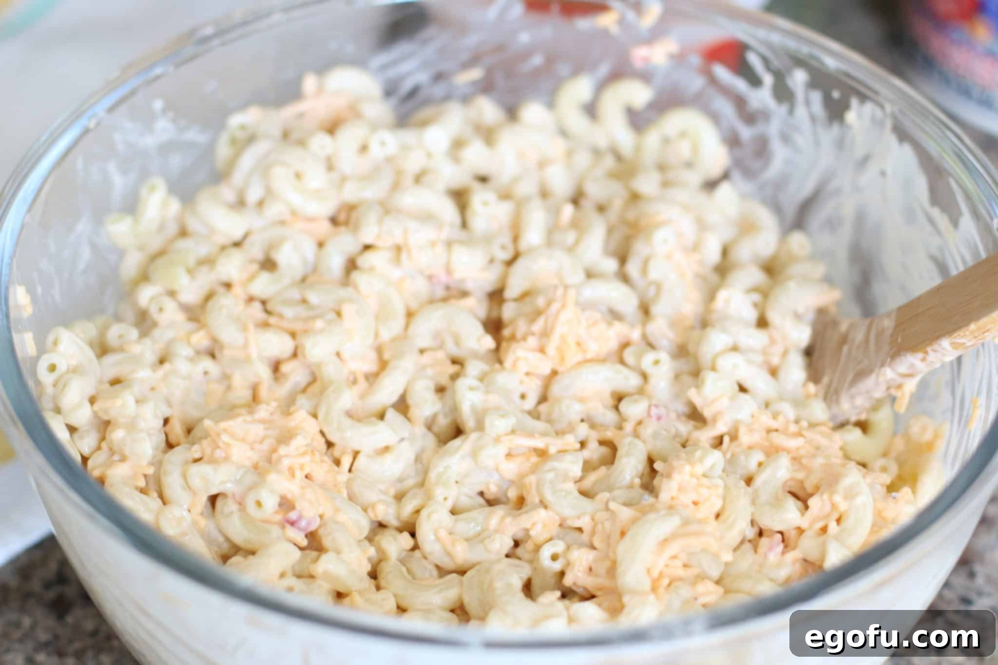 Homestyle Pimiento Macaroni Salad 8 macaroni salad with pimiento cheese and mayonnaise mixture in a large clear bowl.