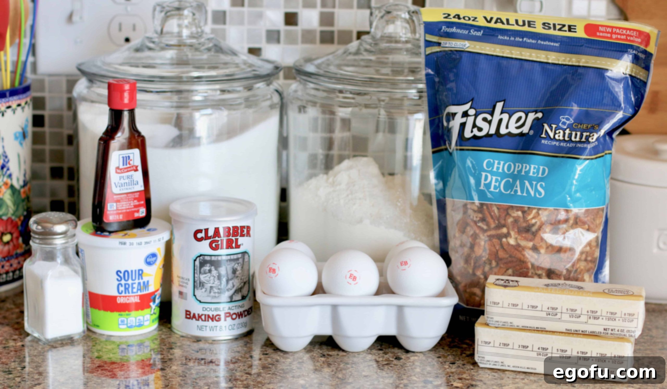 Heirloom Southern Pecan Pound Cake 4 A flat lay photograph displaying all the fresh ingredients required for Southern Pecan Pound Cake: finely chopped pecans, all-purpose flour, baking powder, softened salted butter, granulated sugar, large eggs, pure vanilla extract, and a bowl of creamy sour cream.