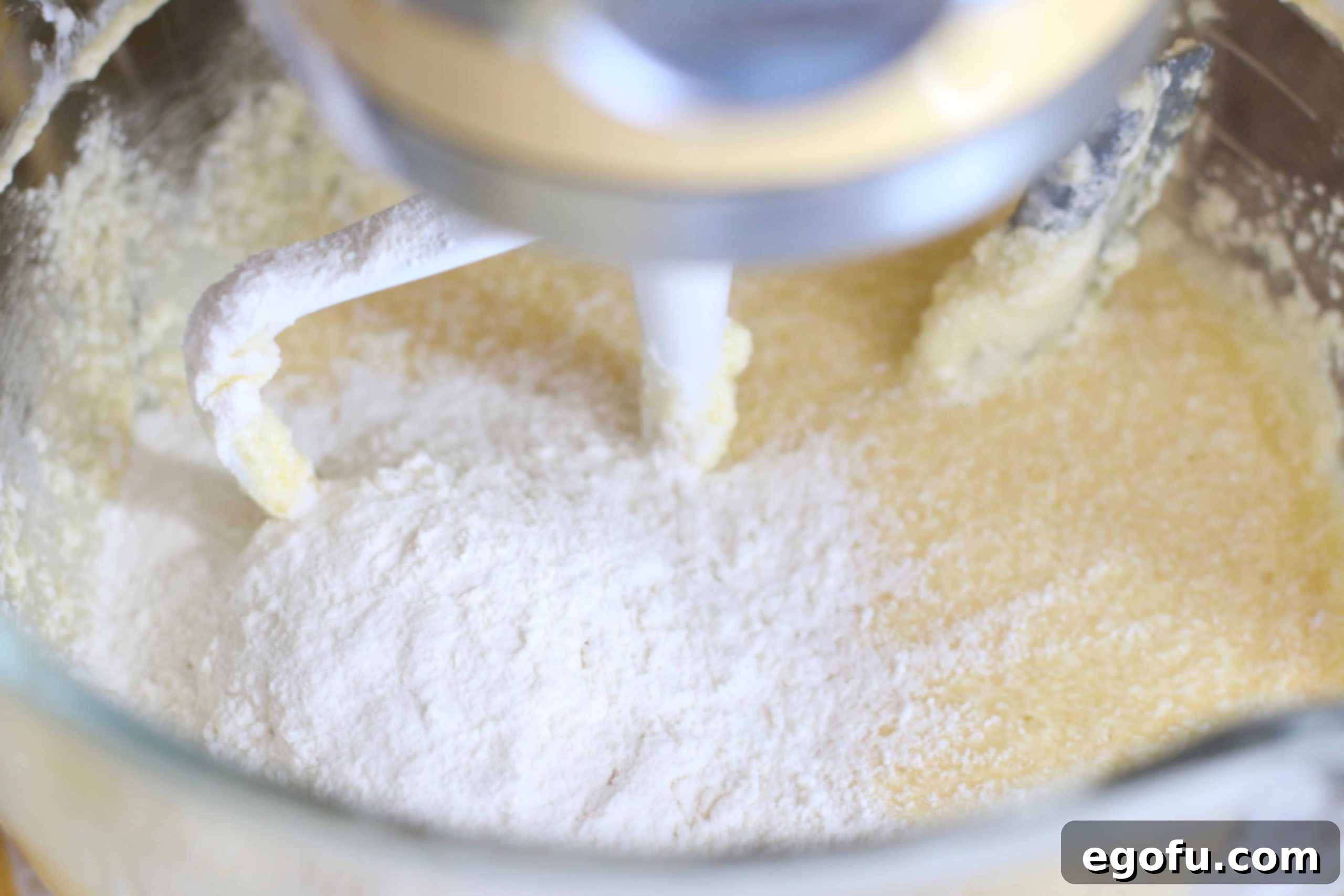 Heirloom Southern Pecan Pound Cake 10 The pre-mixed flour mixture being gently incorporated into the rich butter, sugar, and egg batter in a large mixing bowl, creating a cohesive cake dough.