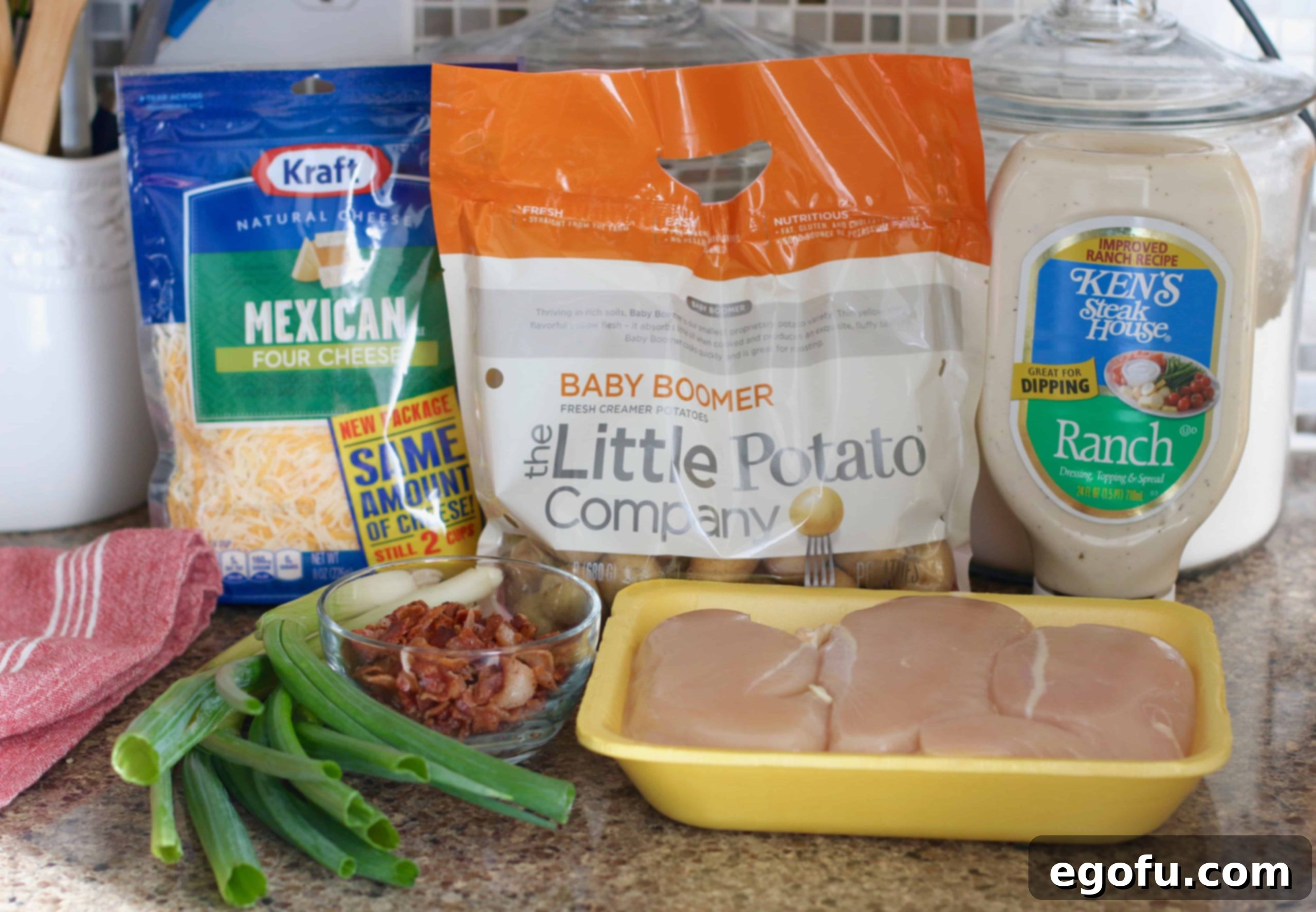 Collection of main ingredients: chicken breasts, shredded cheese, little potatoes, ranch dressing, bacon, green onion for the casserole.
