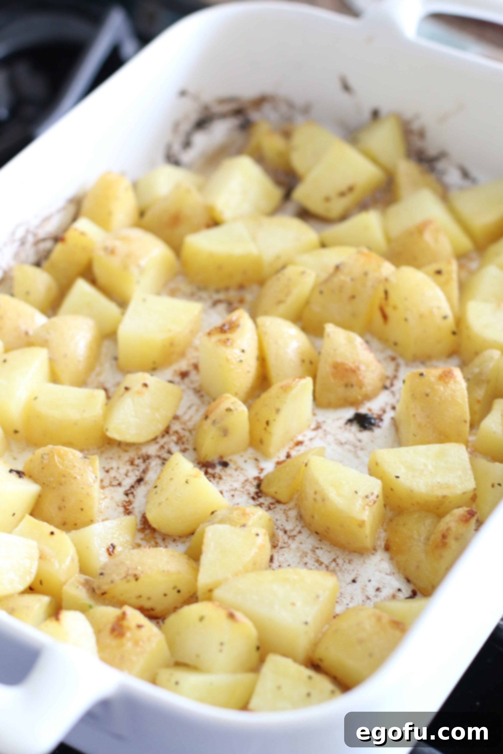 Partially baked, diced potatoes in a casserole dish after 30 minutes of cooking.