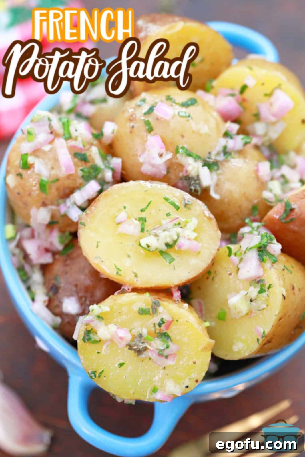 Closeup photo of French Potato Salad in a small blue bowl with handles, showing the vibrant herbs.