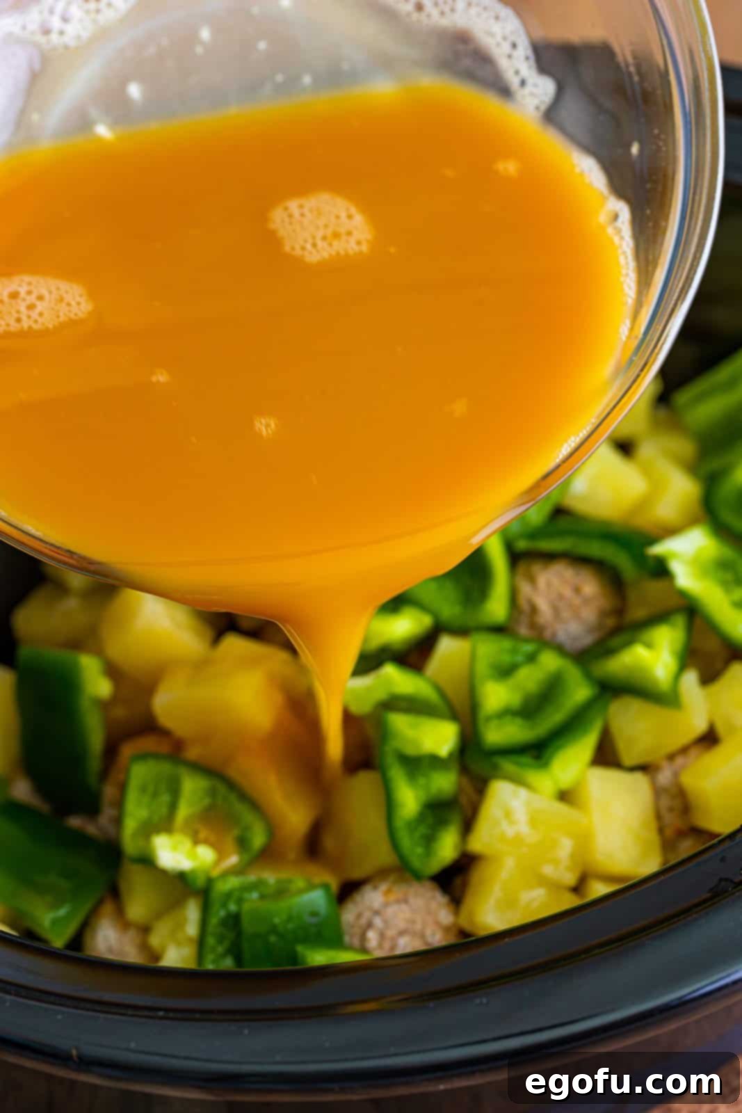 Sticky Sweet & Sour Crockpot Meatballs 10 Pouring sweet and sour sauce into crock pot over green peppers, pineapple and meatballs.