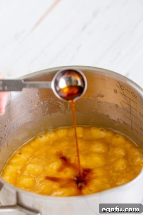 Christmas Caramel Cracker Crunch 13 pouring vanilla extract into brown sugar and butter mixture in a saucepan.