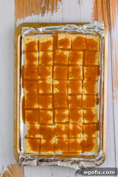 Christmas Caramel Cracker Crunch 14 brown sugar butter mixture poured into crackers on a baking sheet.