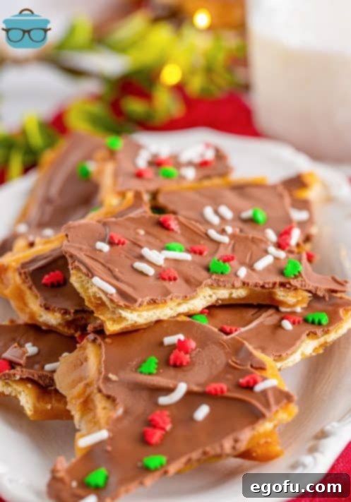 Christmas Caramel Cracker Crunch 17 stack of Christmas cracker toffee on a white platter with a glass of milk in the background.