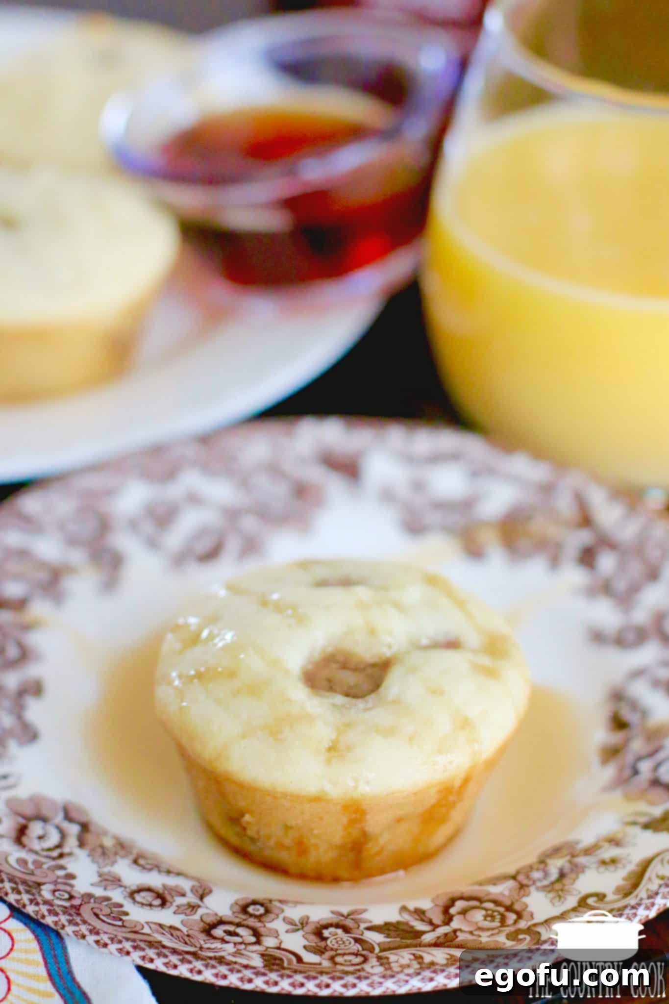 A single pancake sausage muffin on a plate, beautifully topped with a generous pour of golden maple syrup, ready to be enjoyed.