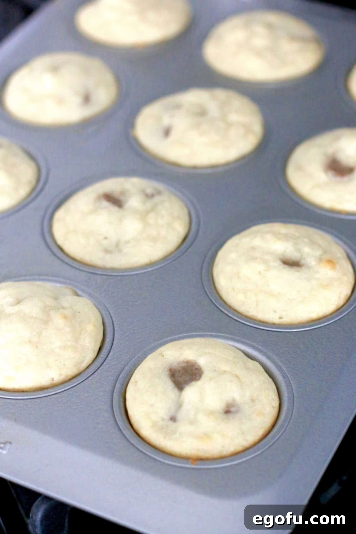 A freshly baked batch of easy pancake and sausage muffins, still in the muffin pan, with a light golden hue on their tops.