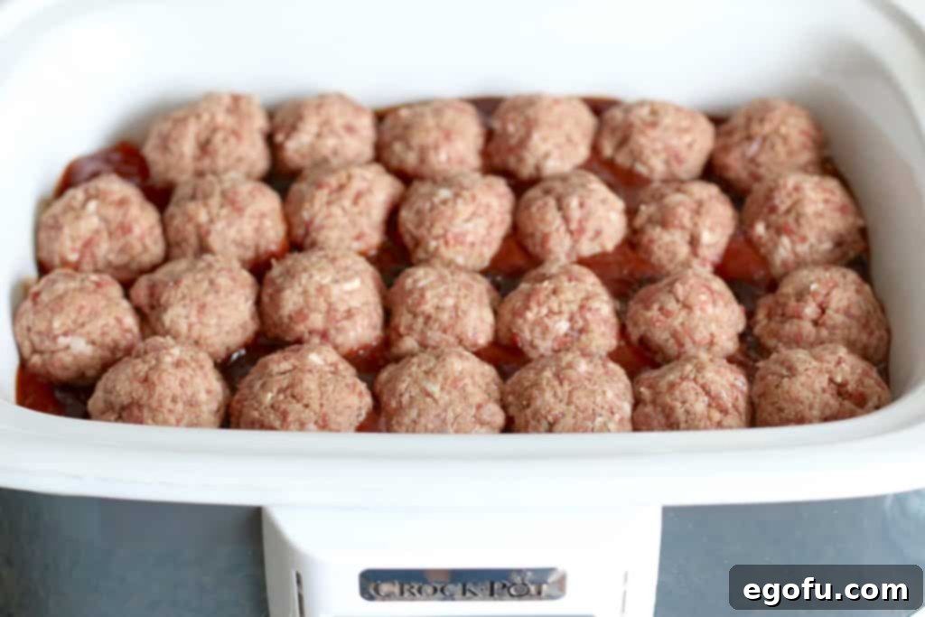 homemade meatball (uncooked) placed on top of jelly sauce mixture