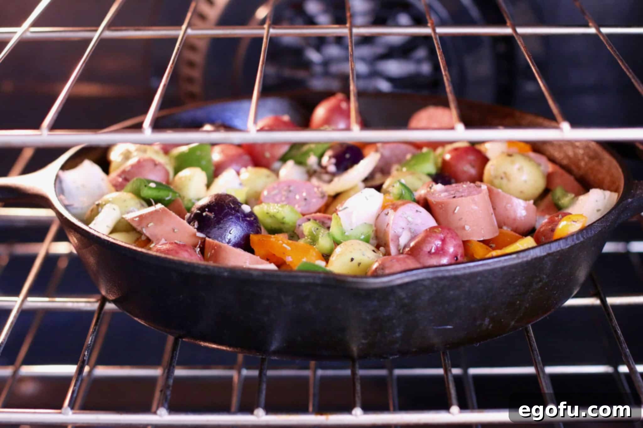 One pan sausage and potatoes baking in a skillet in the oven.