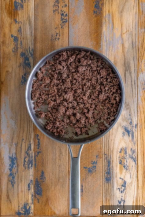 Okinawan Taco Rice 10 brown and crumbled ground beef in a skillet.