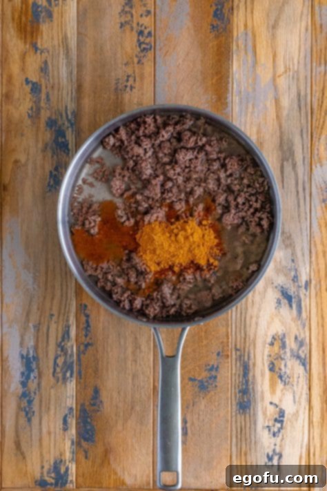 Okinawan Taco Rice 11 water and taco seasoning added to cooked ground beef in a skillet.