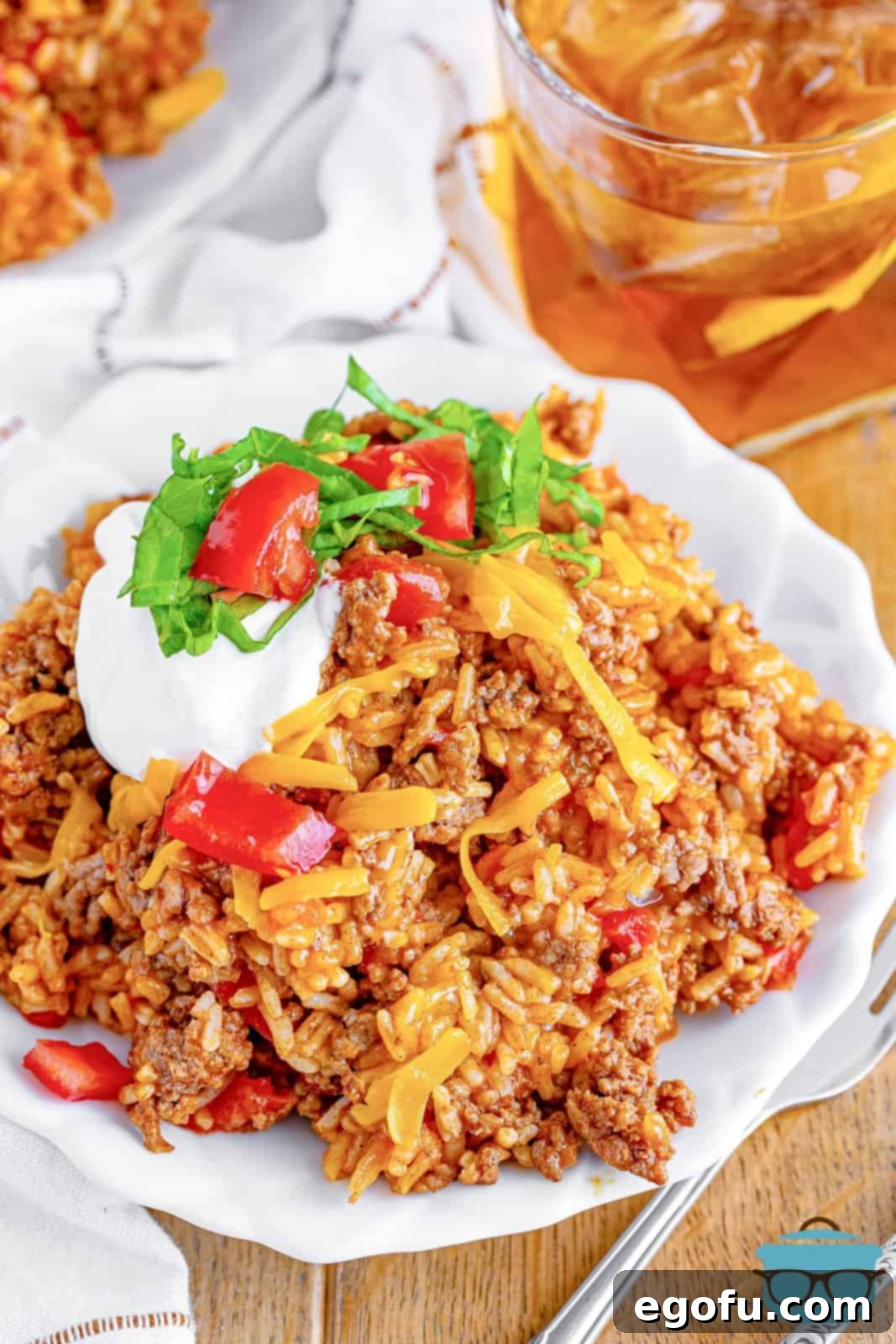 Okinawan Taco Rice 9 Taco Rice shown served on a white plate and topped with sour cream, lettuce and tomato.