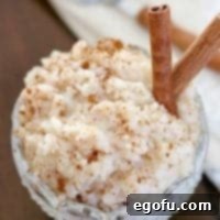 Creamy Crock Pot Rice Pudding 11 rice pudding in a decorative clear glass dessert bowl with two cinnamon sticks