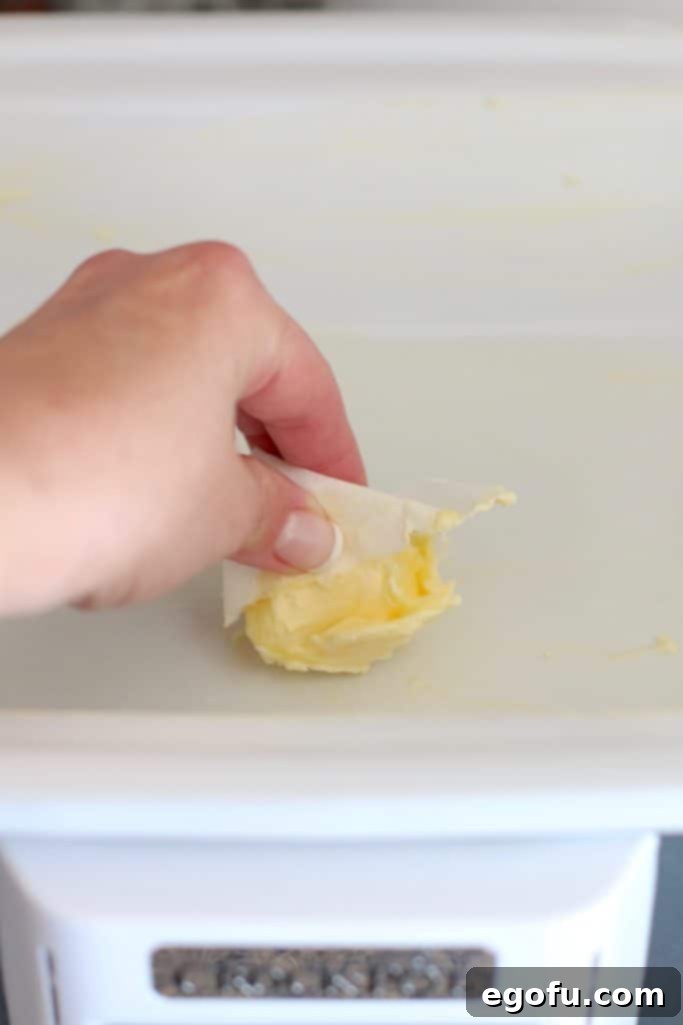 Creamy Crock Pot Rice Pudding 5 spreading butter in a crock pot.