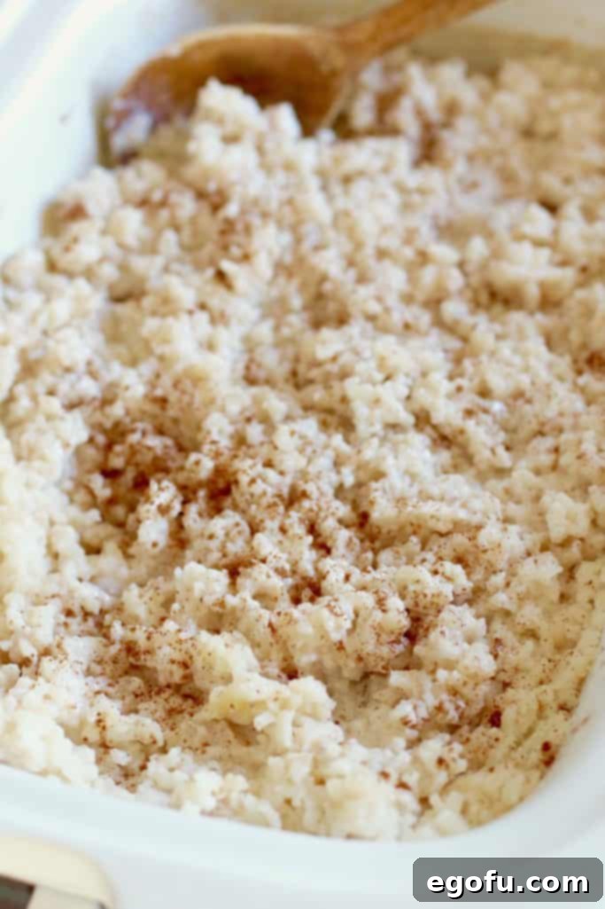 Creamy Crock Pot Rice Pudding 9 finished crock pot rice pudding in a casserole slow cooker topped with ground cinnamon.