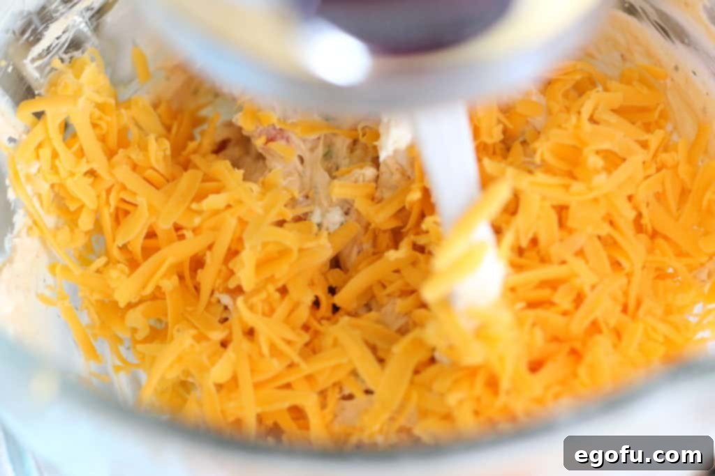 The Great Pumpkin Cheese Ball 11 shredded cheddar cheese mixture added to cream cheese mixture.