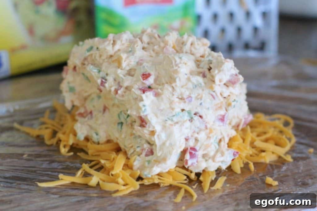 The Great Pumpkin Cheese Ball 13 vegetable cheeseball mixture spread on top of cheese and plastic wrap.