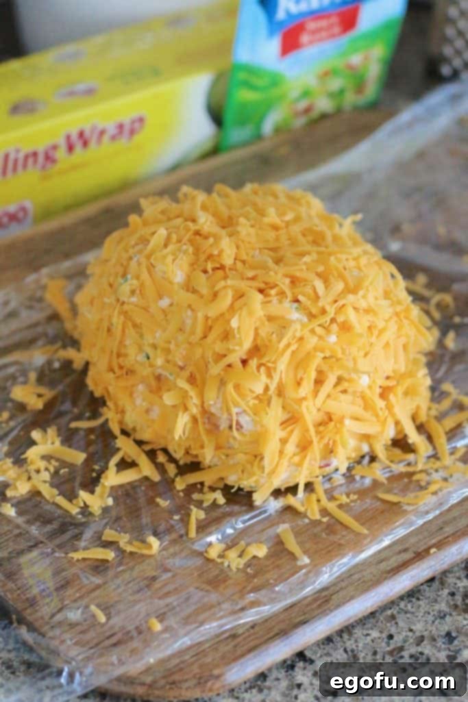The Great Pumpkin Cheese Ball 14 shredded cheddar cheese evenly spread all over vegetable cheeseball.