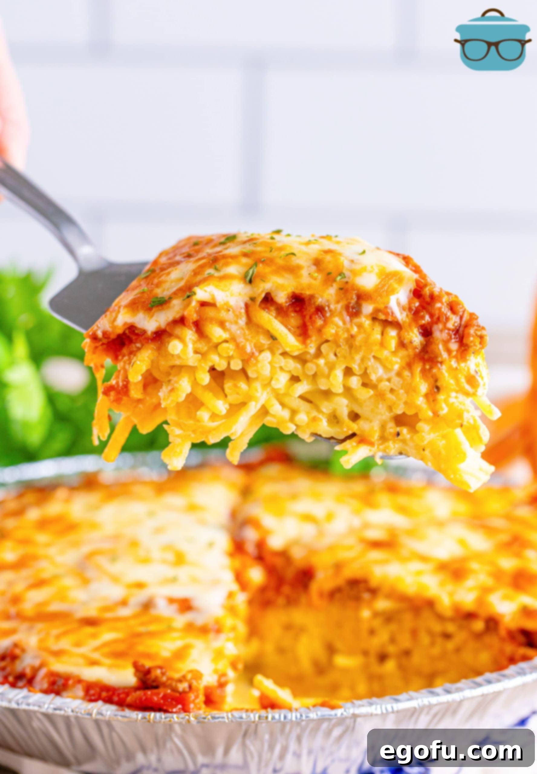 A pie server holding a serving of Spaghetti Pie above the pie plate. 