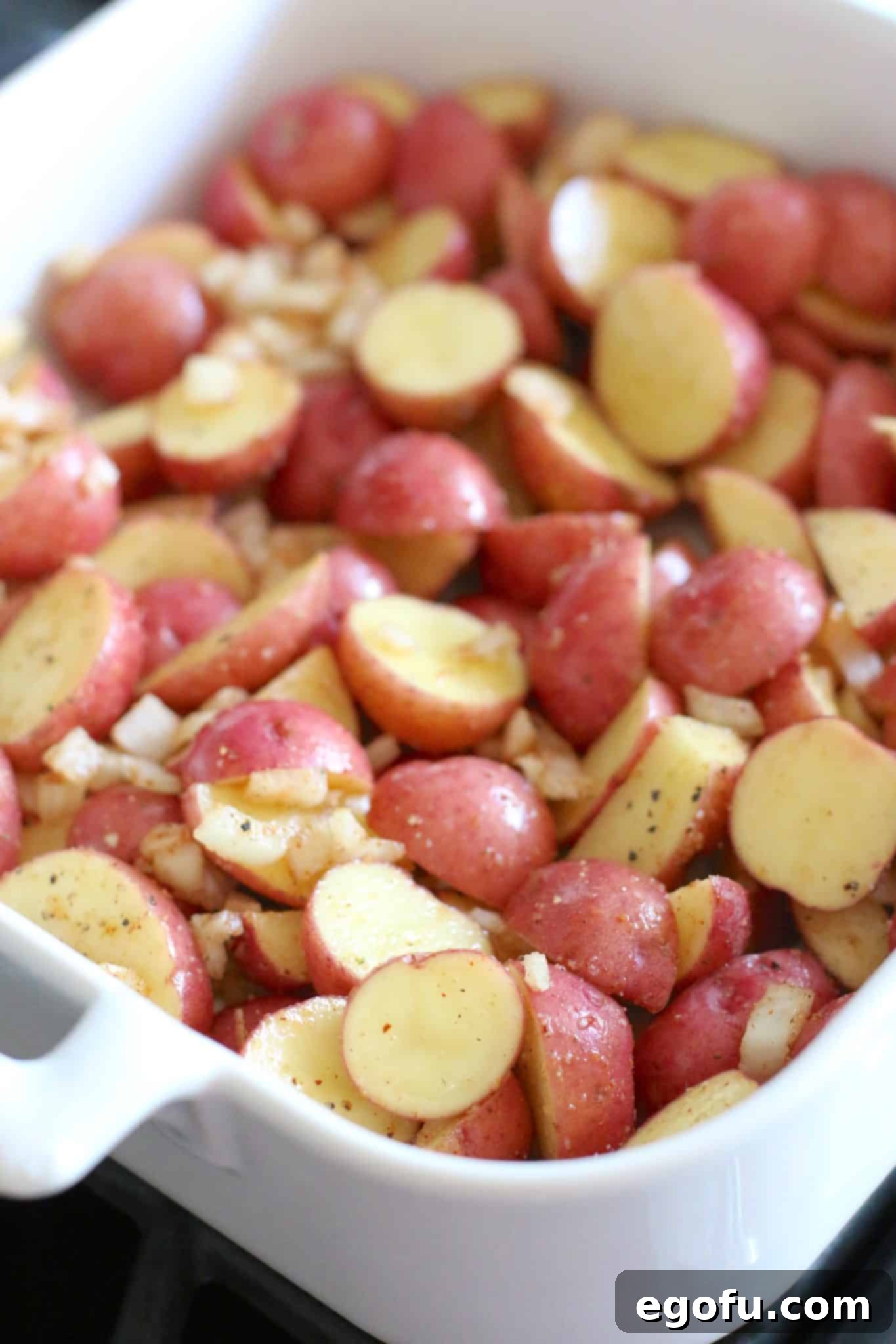 Seasoned, sliced baby red Little Potatoes in a white Revol baking dish.