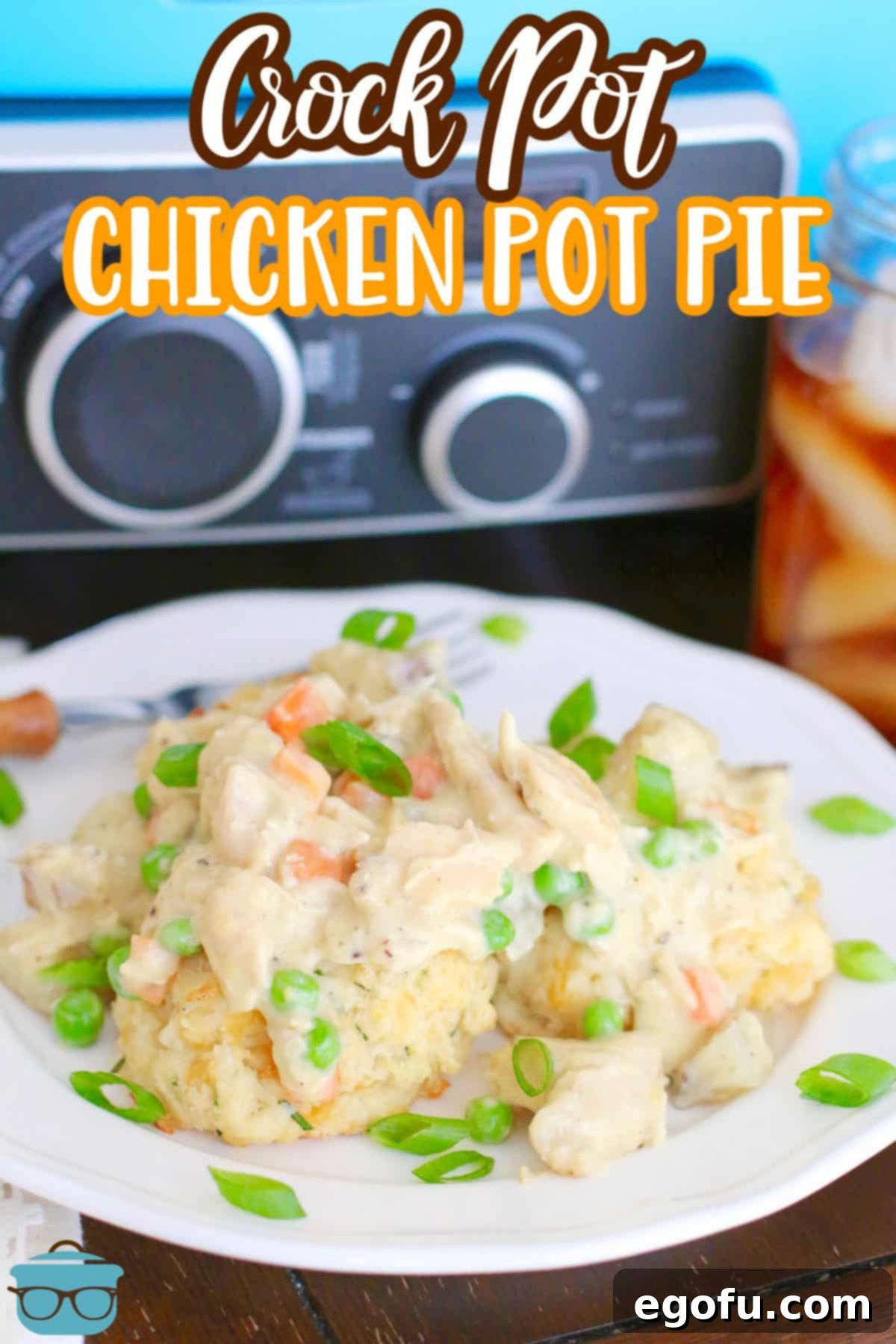 a white plate topped with biscuits and chicken pot pie filling sitting in front of a blue slow cooker and a glass of iced tea.