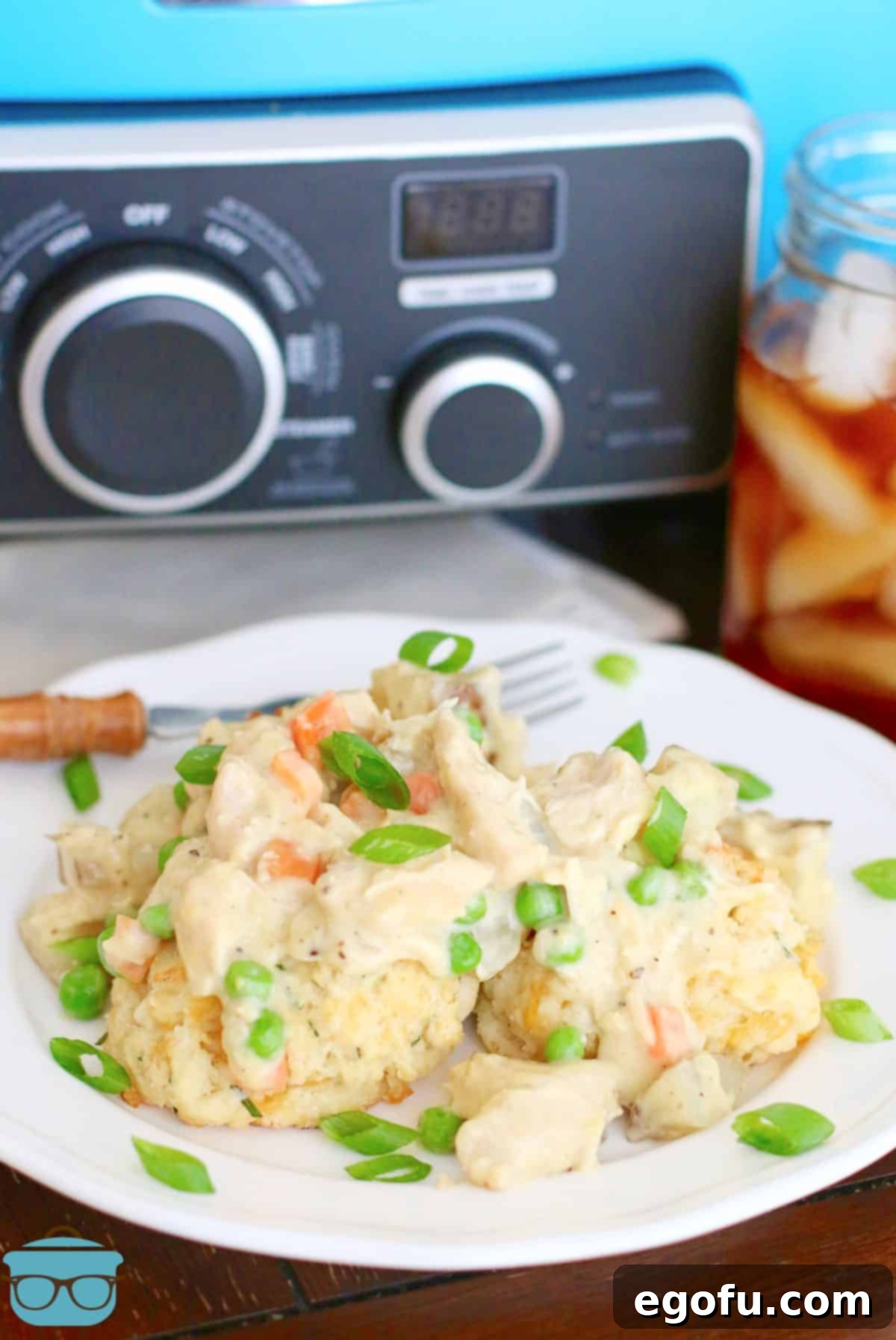 plate of chicken pot pie filling on biscuits in front of a blue crock pot.