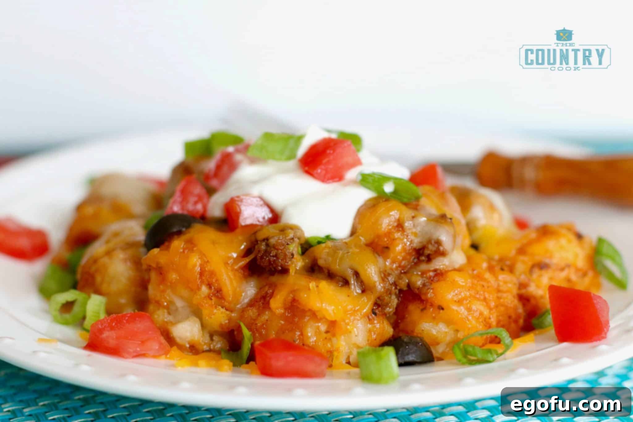 Tater Tot Enchilada Bake serving shown on a round white plate, topped with fresh herbs.