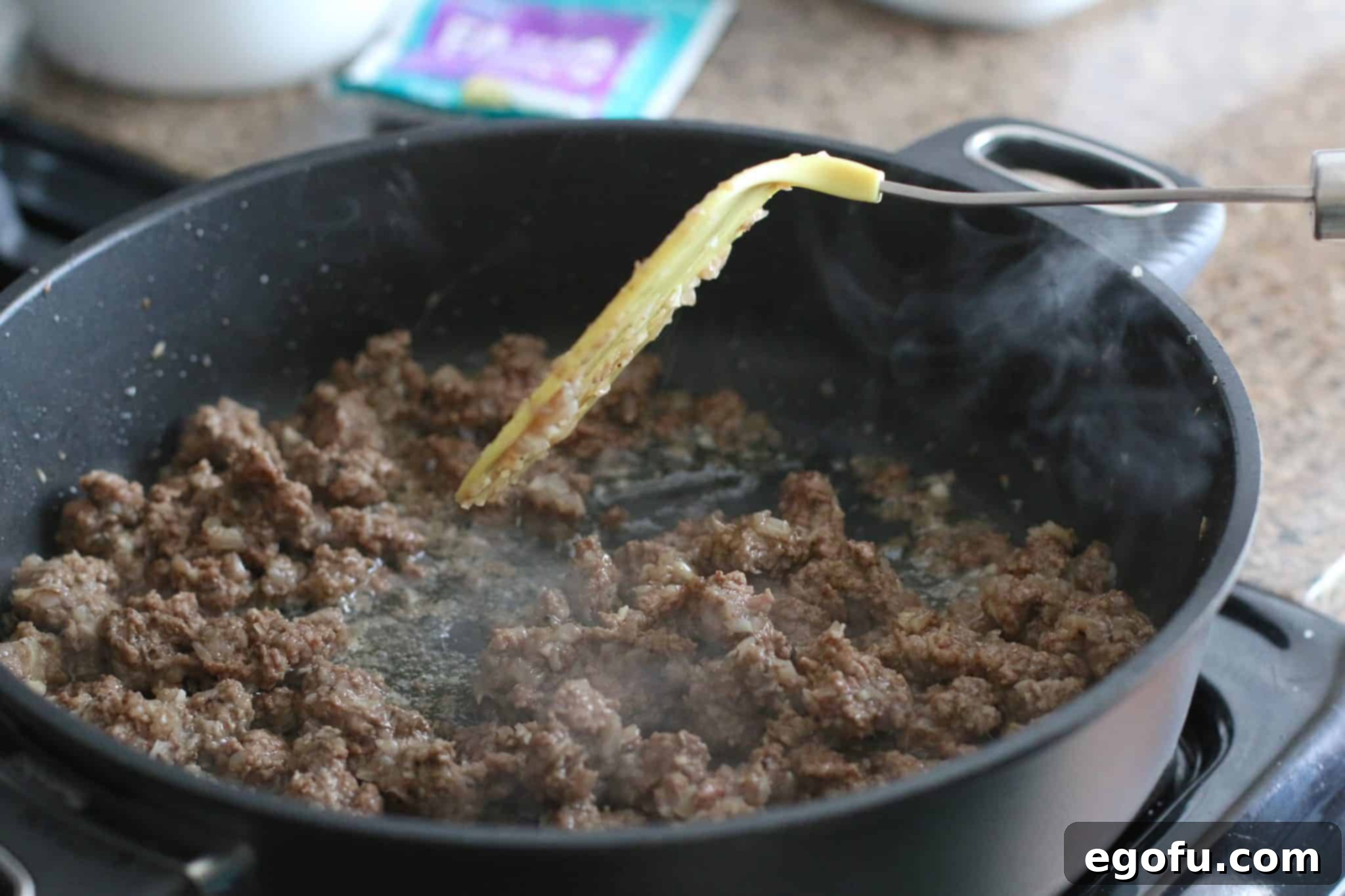 Browned and crumbled ground beef in a large skillet, having been drained of excess fat.