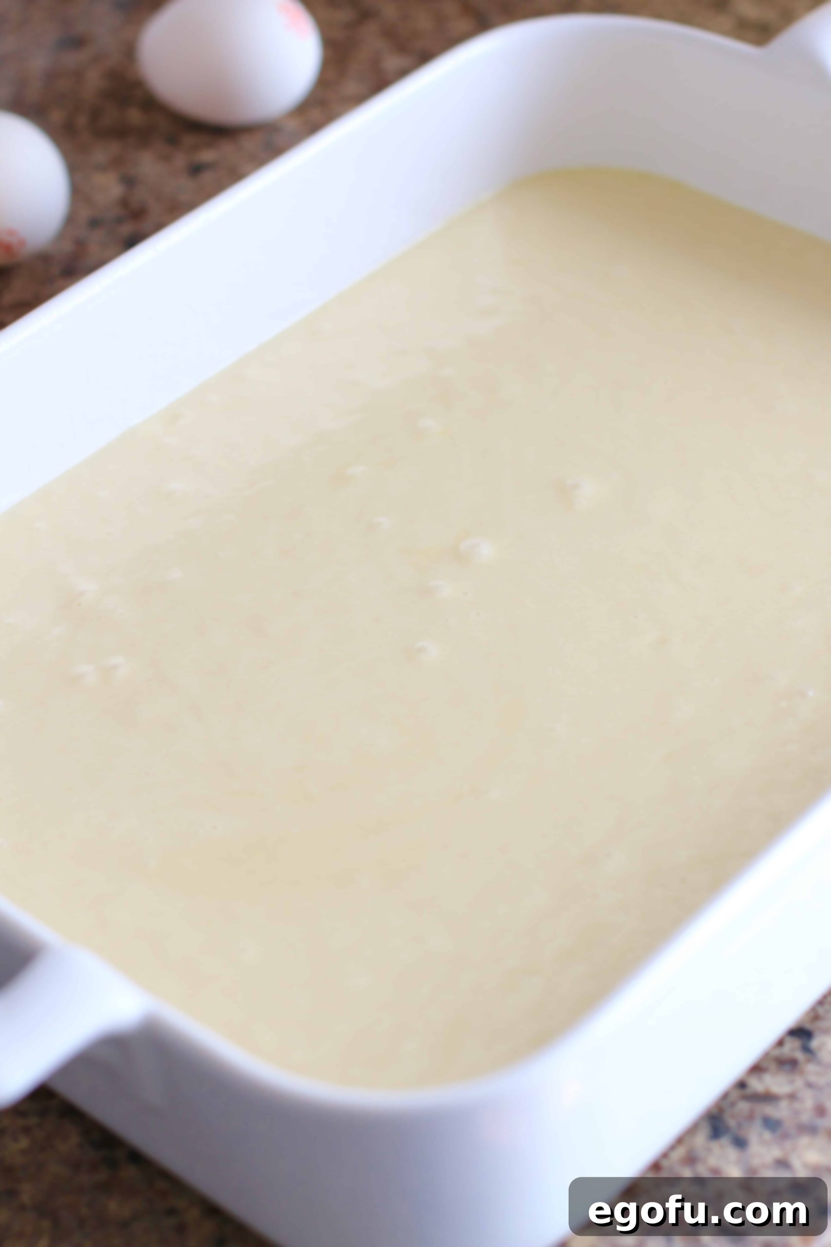 Harvest Moon Pumpkin Dream 7 Smooth vanilla cake batter already poured into a white ceramic baking dish, forming the first layer of the cake.