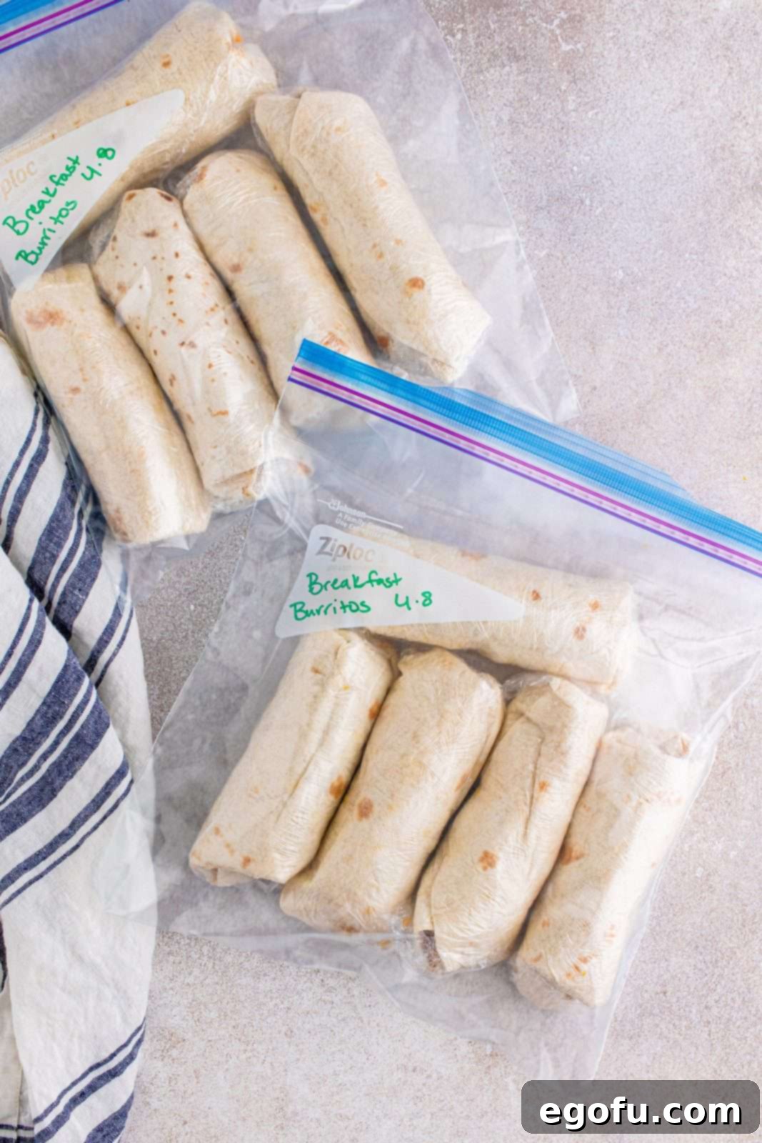 Wrapped breakfast burritos neatly stacked inside freezer-safe bags, clearly labeled for convenient storage.