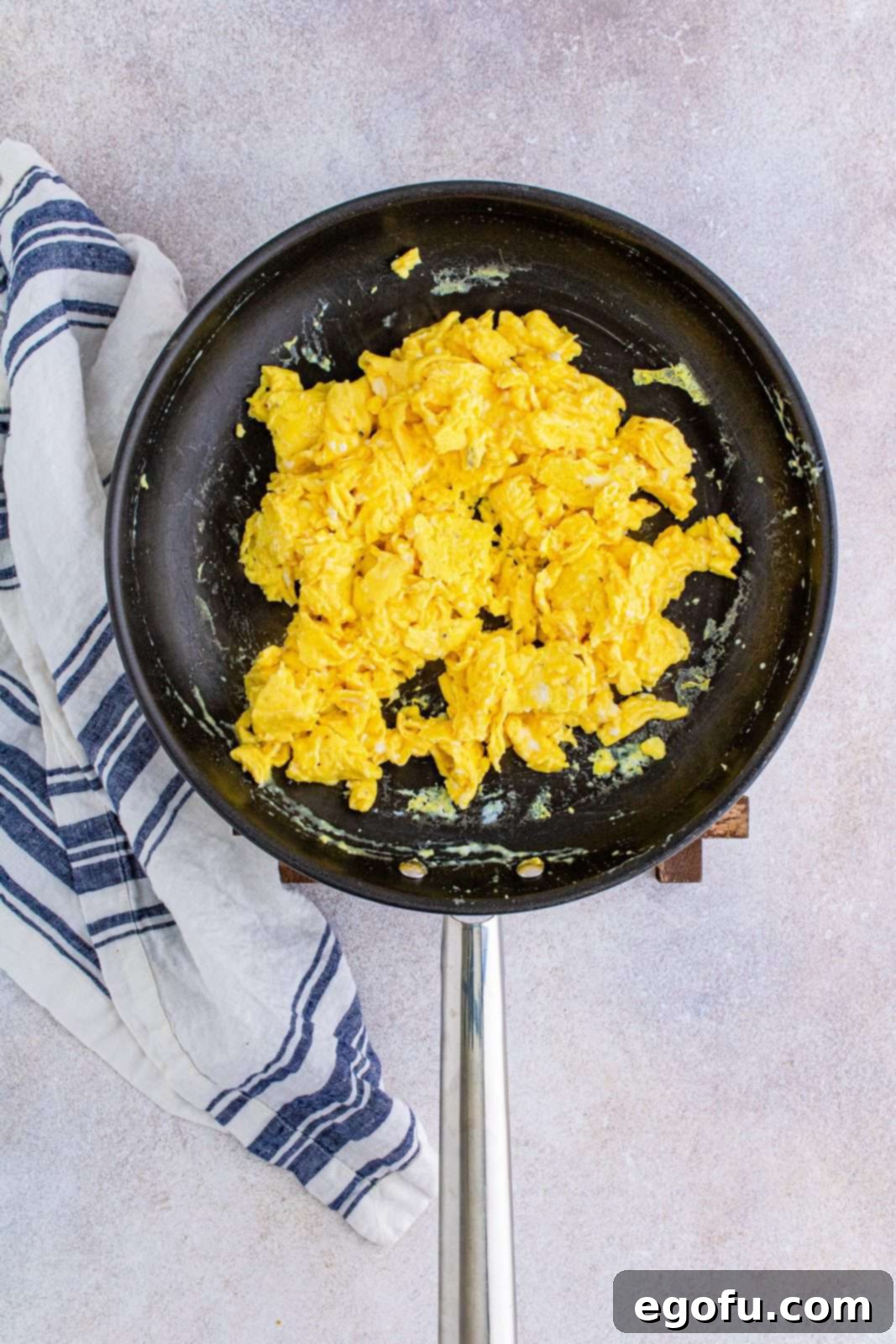Fluffy scrambled eggs cooking in a skillet over low heat, being gently stirred with a spatula.