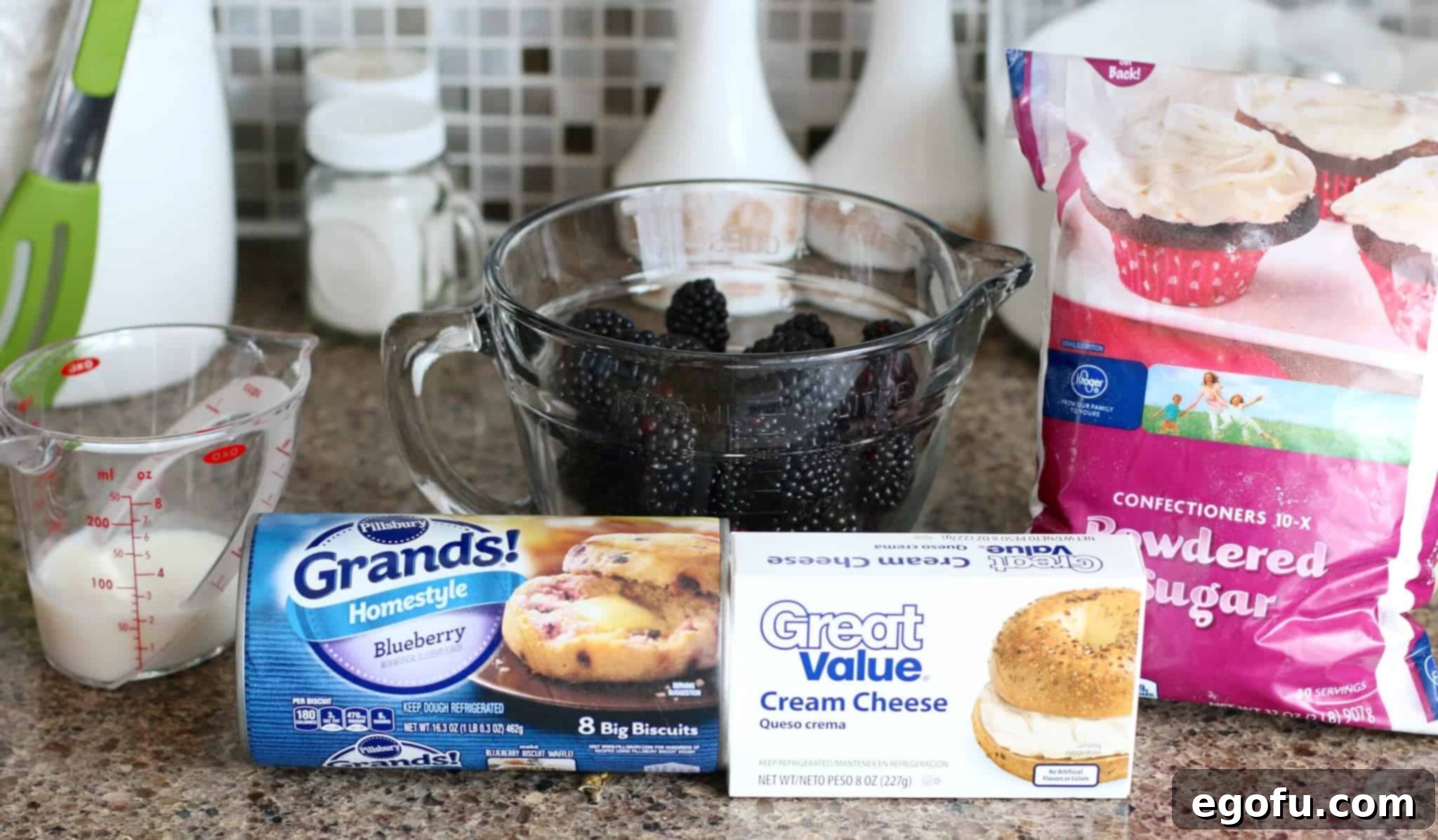 Blackberry Burst Bake 4 A flat lay of all the ingredients needed for Blackberry Bubble Up: refrigerated blueberry biscuits, fresh blackberries, cream cheese, powdered sugar, and milk.