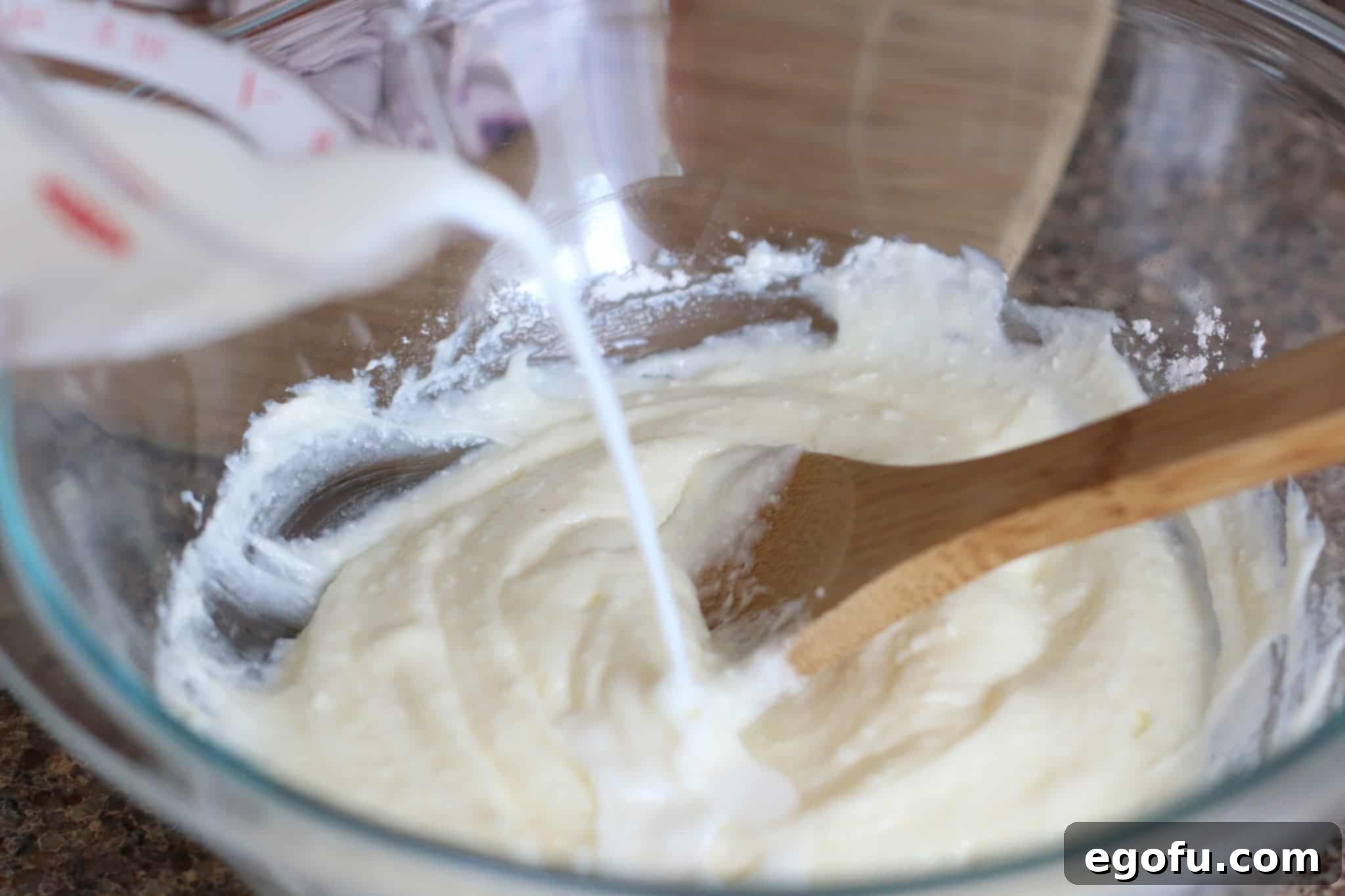 Blackberry Burst Bake 7 Milk being poured into the smooth cream cheese and powdered sugar mixture in a bowl.