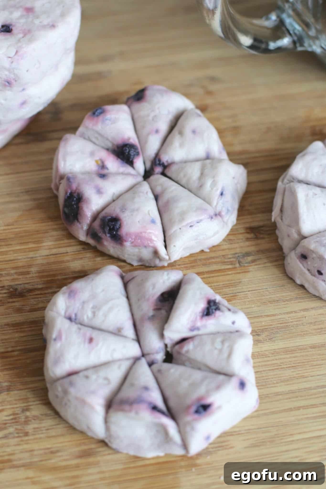 Blackberry Burst Bake 9 Refrigerated blueberry biscuits cut into eighths on a wooden cutting board.