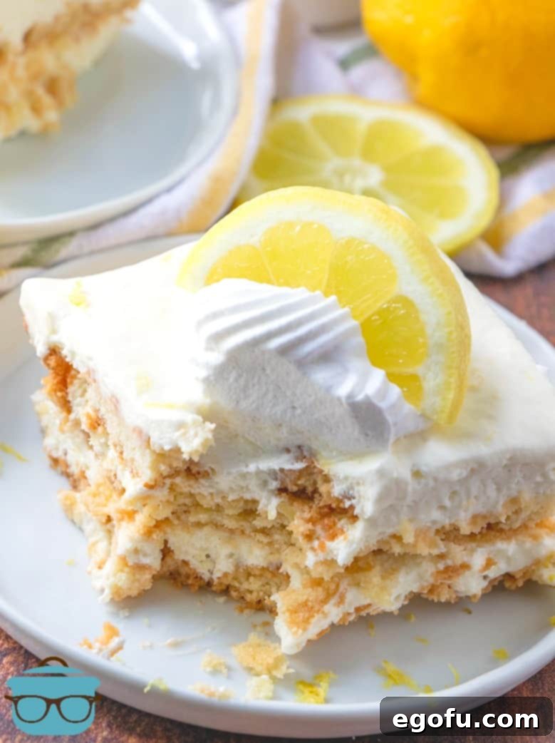 Zesty Lemon No-Bake Delight 2 No-Bake Lemon Icebox Cake slice served on a white plate topped with a dollop of whipped cream and a lemon slice.