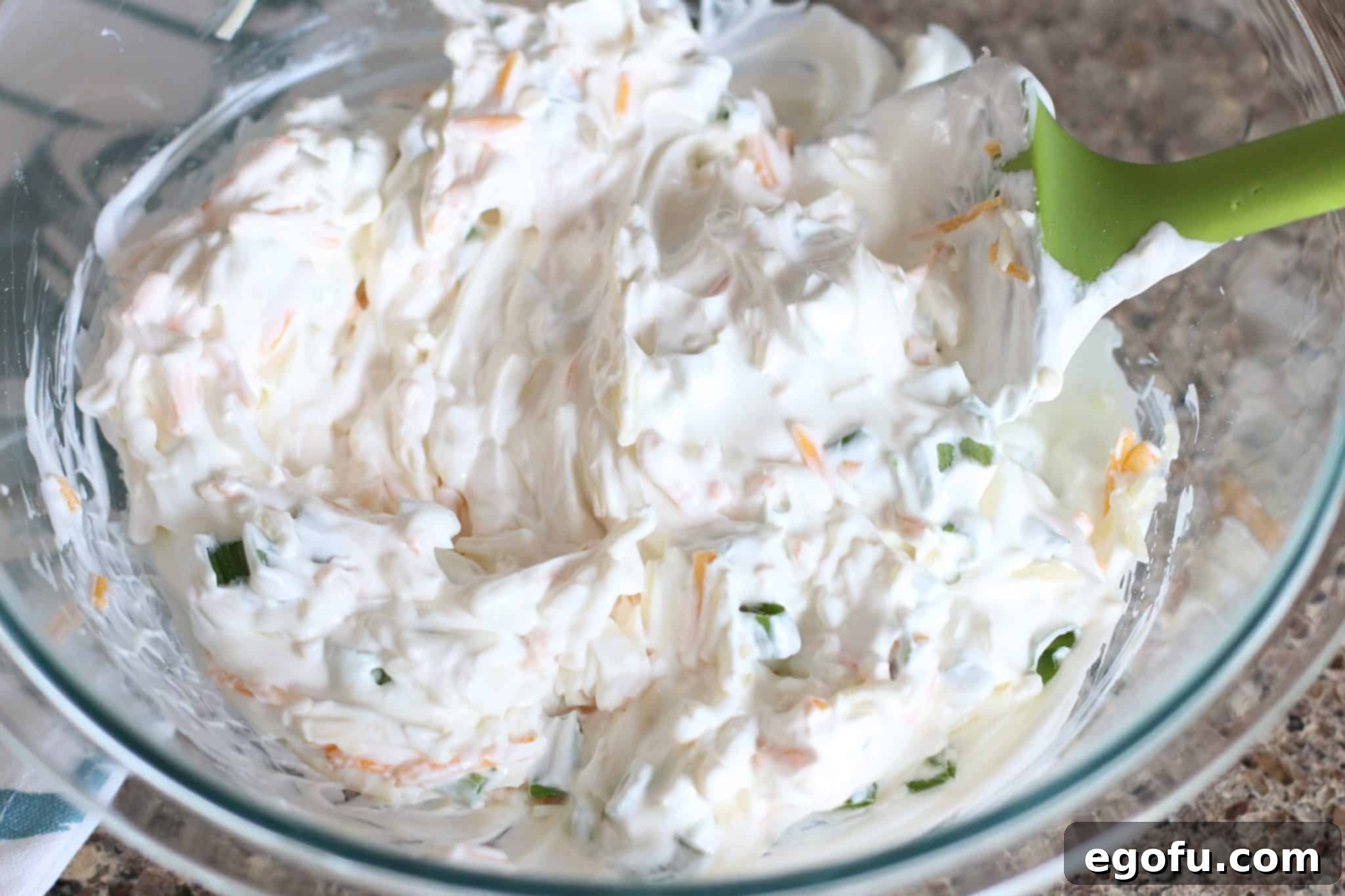 sour cream, shredded cheddar cheese, sliced green onion mixed together in a clear bowl.