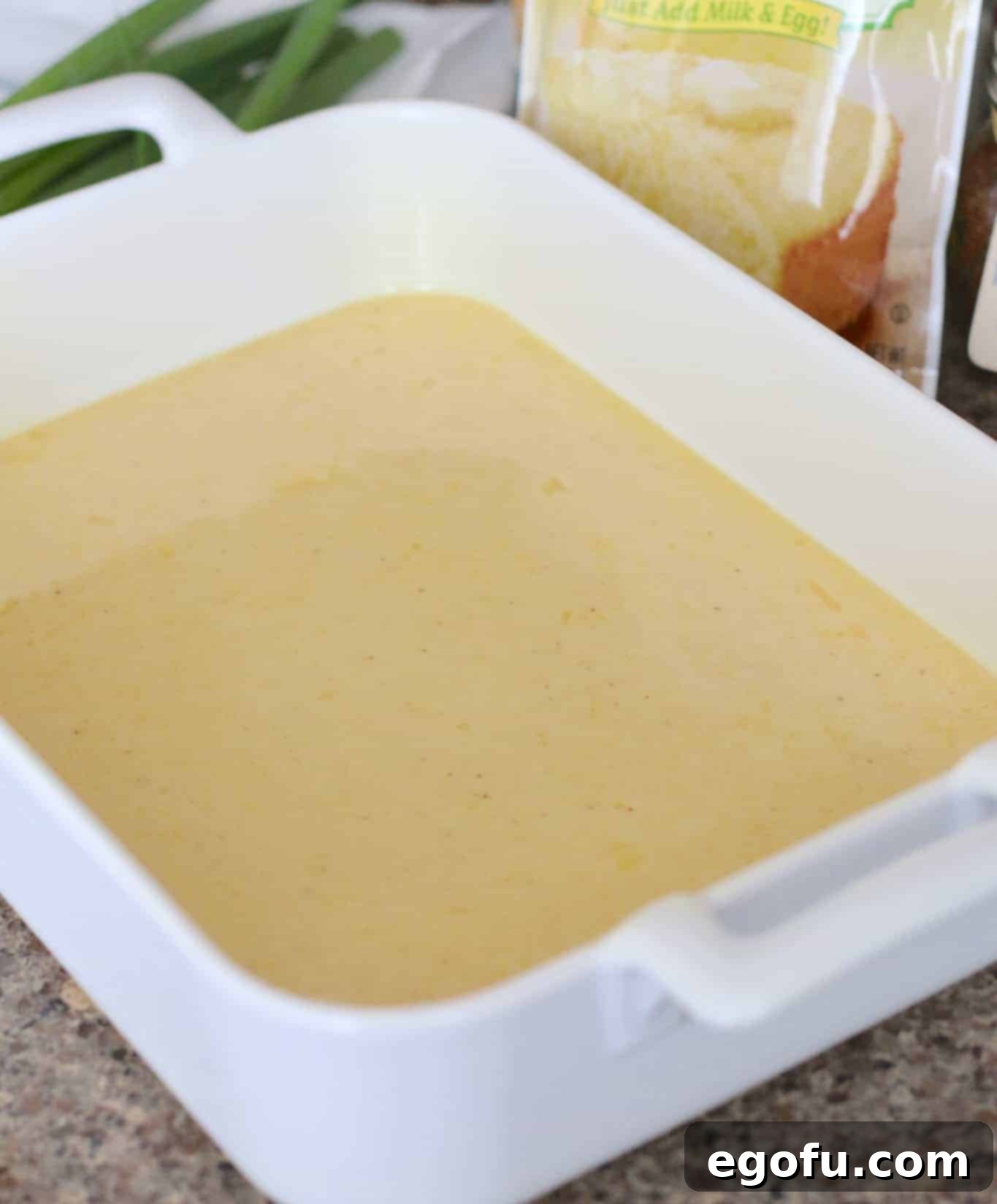 Cornbread batter in a square white baking dish.