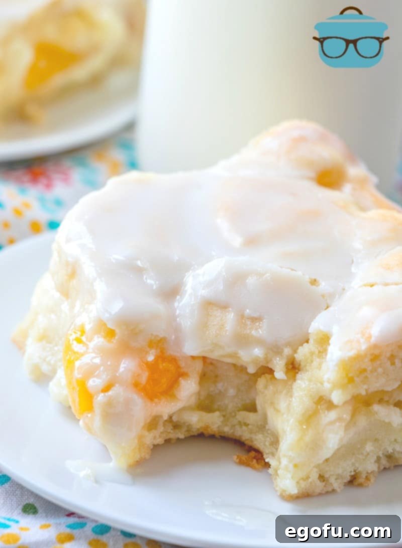 Velvet Peach Cream Bars 14 A tempting slice of Peaches and Cream Bars, with a bite already taken, showcasing its moist texture and delicious layers of crust, cheesecake, and peach filling.