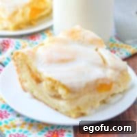 Velvet Peach Cream Bars 15 A single slice of Peaches and Cream Bars presented on a white plate, highlighting its delicious layers and crumbly top, ready to be enjoyed.