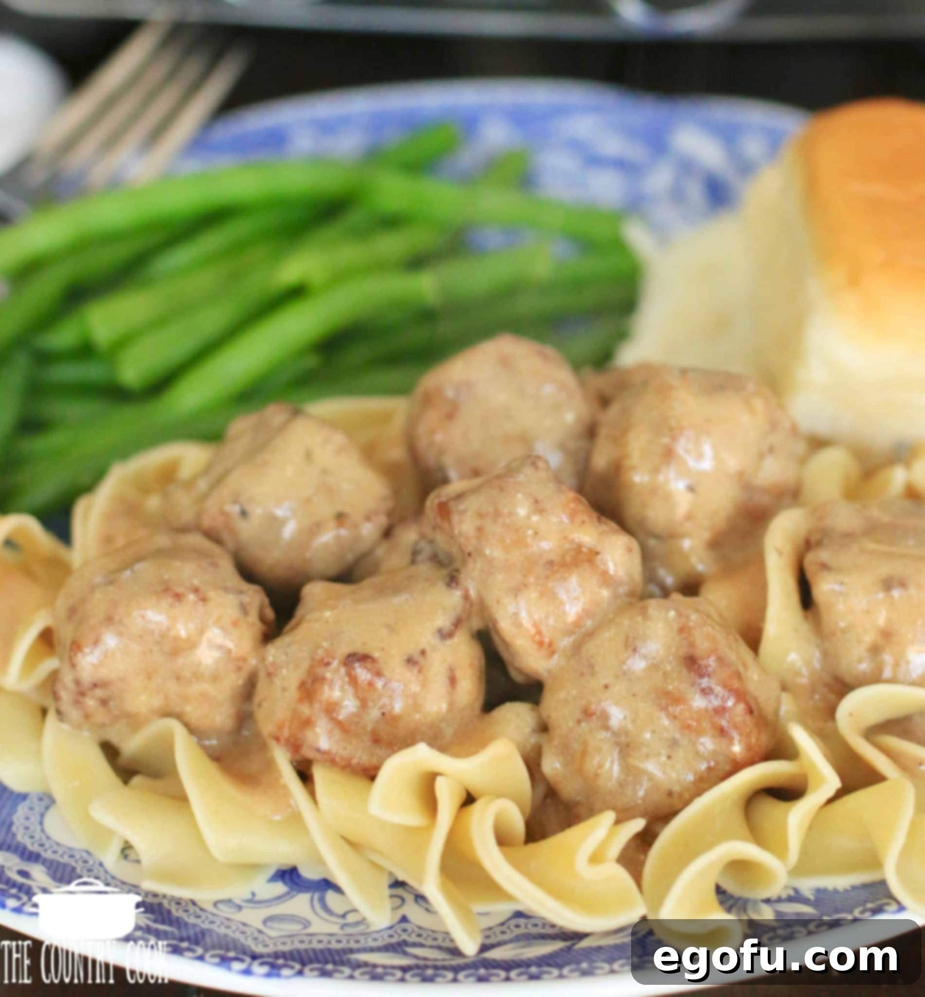 Close-up of Slow Cooker Meatballs in rich, creamy Gravy Sauce, garnished with fresh herbs, ready to be served.