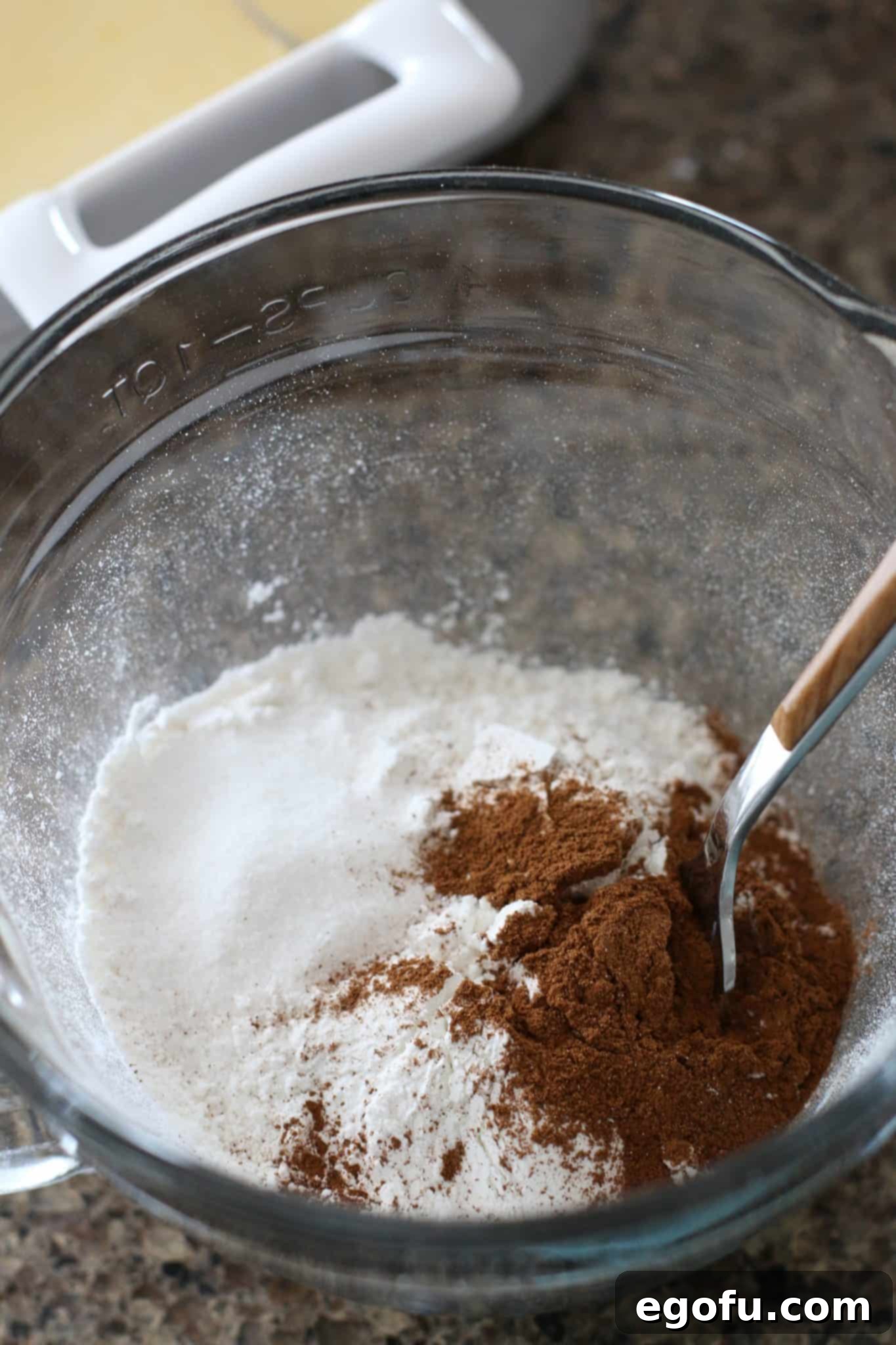 Pillowy French Toast Perfection 5 flour, cinnamon, baking powder, and sugar being mixed together with a fork in a clear measuring cup.