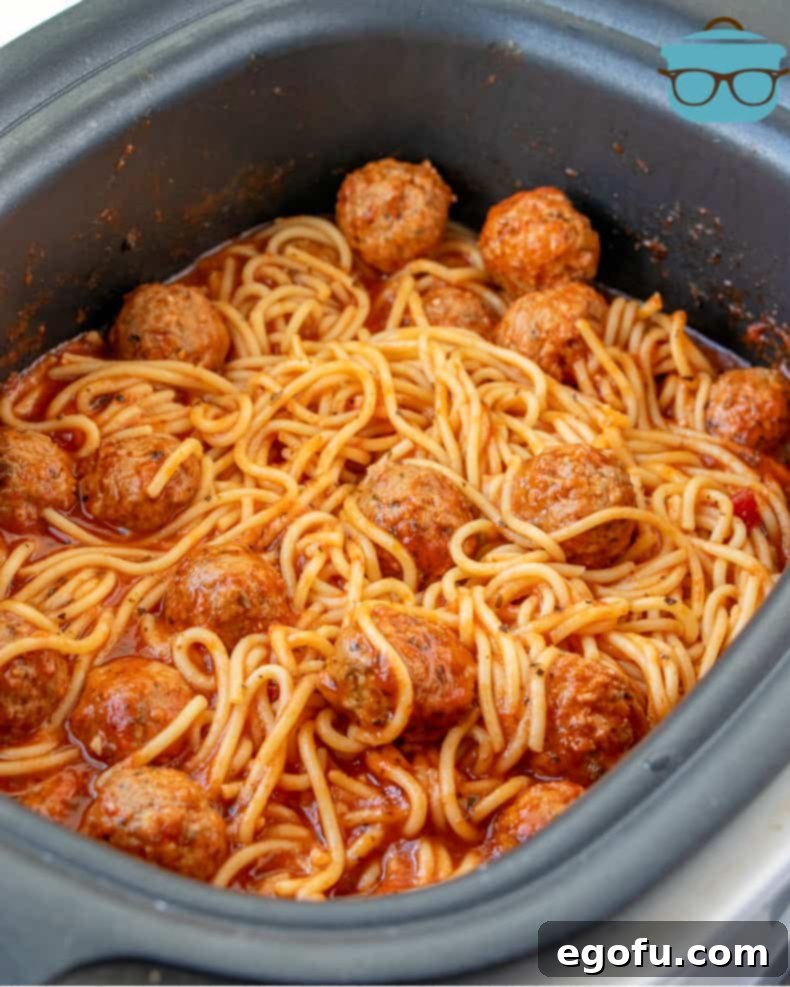 Effortless Slow Cooker Spaghetti and Meatballs 11 Cooked spaghetti and meatballs, gently stirred in the slow cooker, showing the rich sauce and tender pasta.